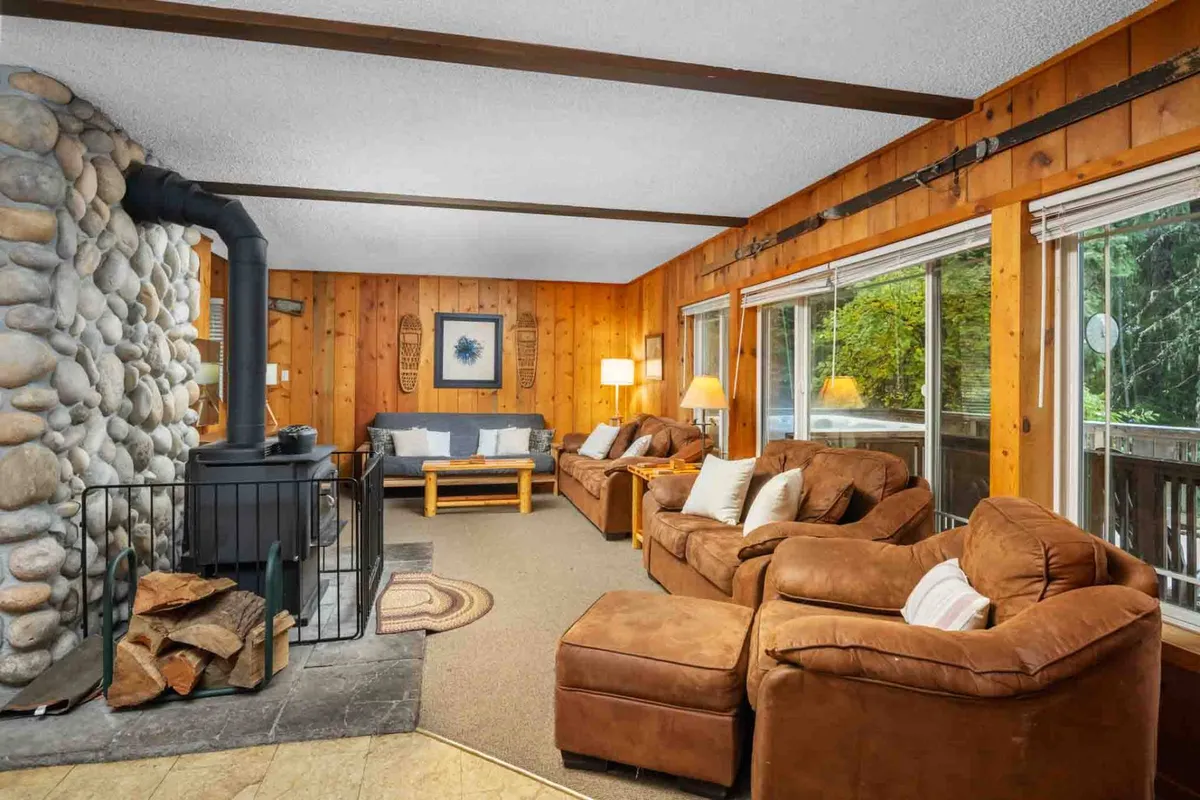 An inviting living room filled with leather sofas, a stone fireplace, and large windows that provide views of the surrounding greenery. The space is ideal for relaxing, unwinding, and gathering with friends or family after a day spent outdoors.