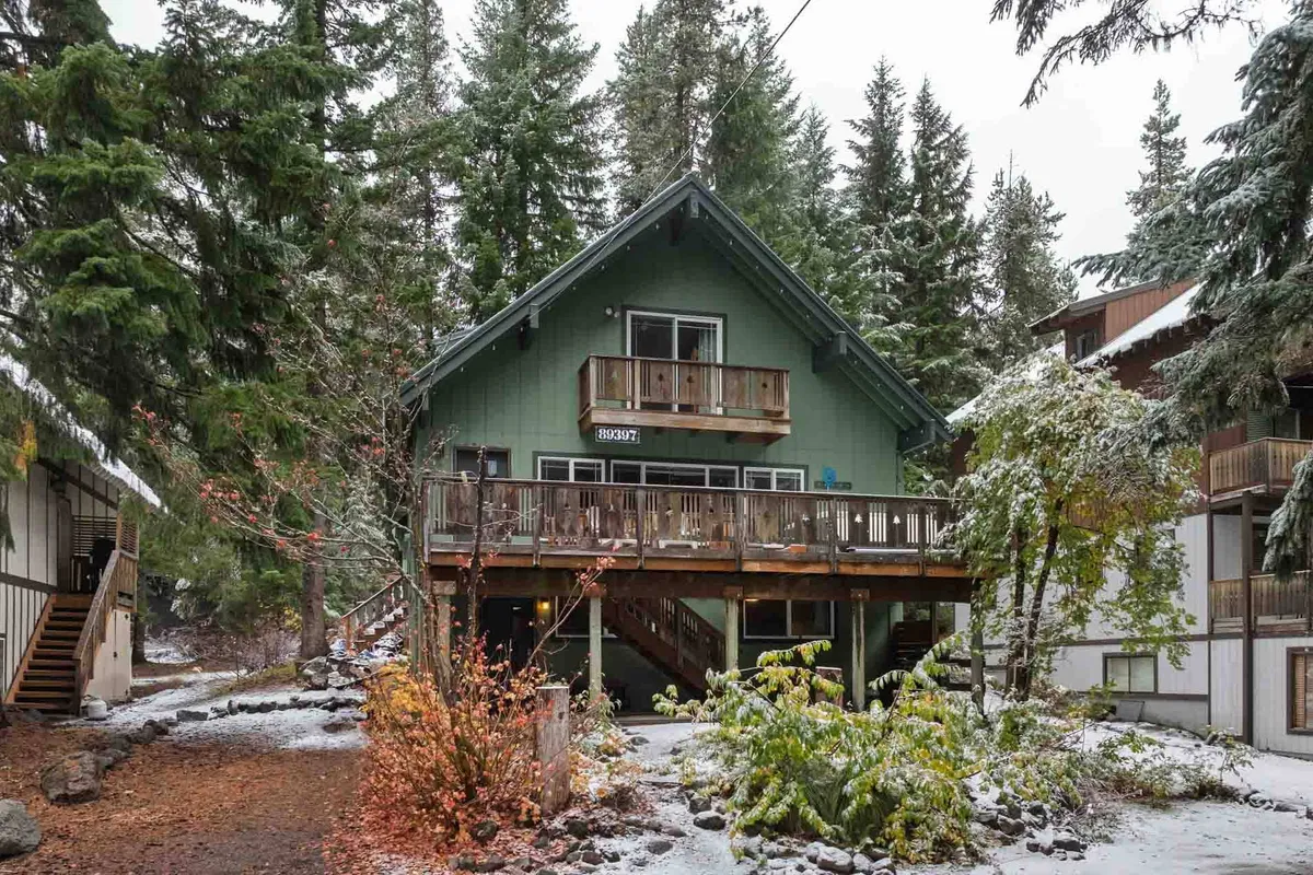 This exterior image features the chalet’s green facade and balcony set amidst a snowy landscape, surrounded by tall trees. The snow-covered ground suggests easy access to winter activities, while the inviting balcony hints at relaxation after outdoor adventures.